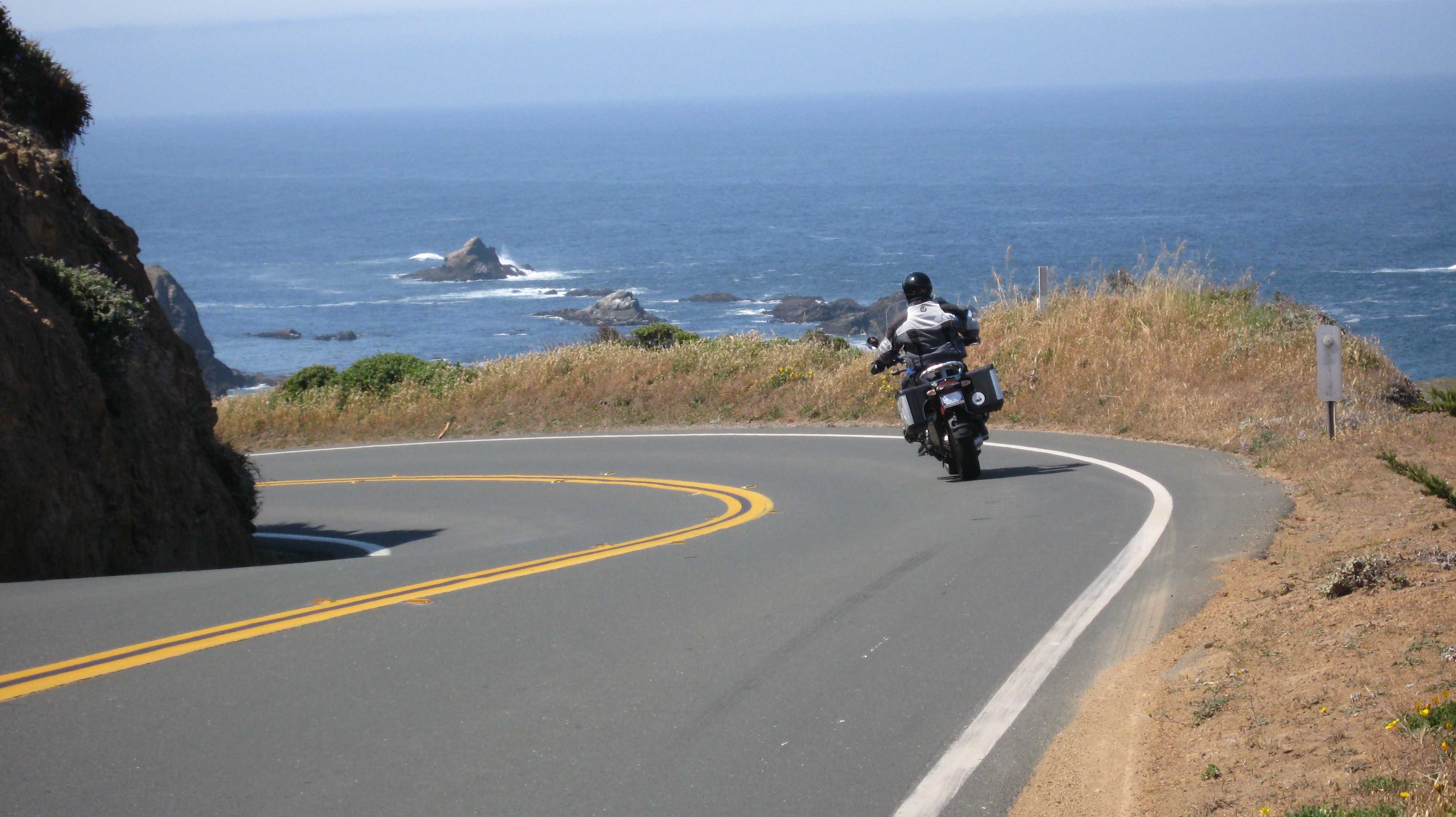 Мотоцикл едет по дороге. Мотоцикл на дороге. Мотоцикл едет. Мотоцикл для путешествий. Мото и море.